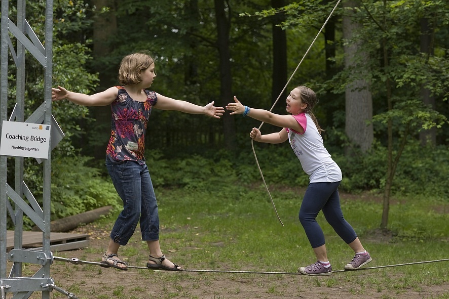 Kinder spielen im Wald. Beide stehen auf einem Seil das wackelt