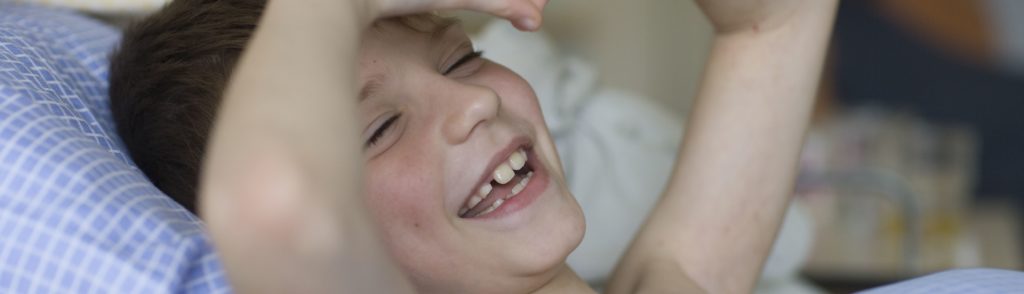 Ein Junge liegt im Krankenhausbett. Nahaufnahme des Gesichts welches glücklich aussieht