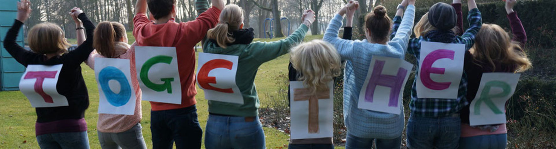Menschen mit einzelnen Buchstaben auf dem Rücken. Sie bilden das Wort Together